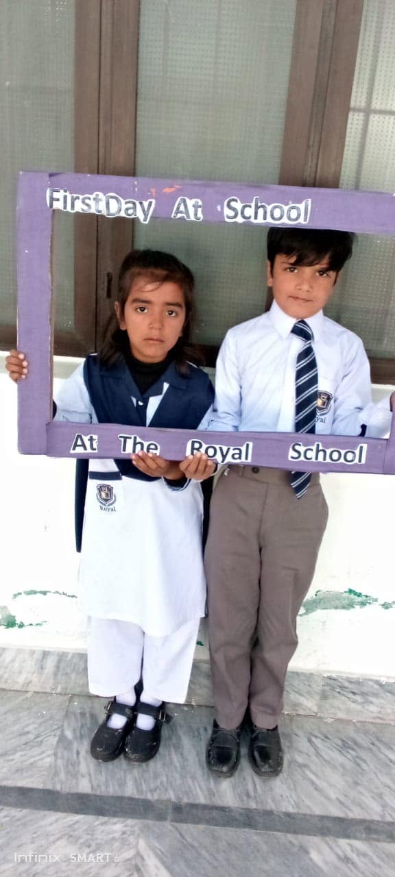 Royal School pupils posing with a First Day at School welcome frame